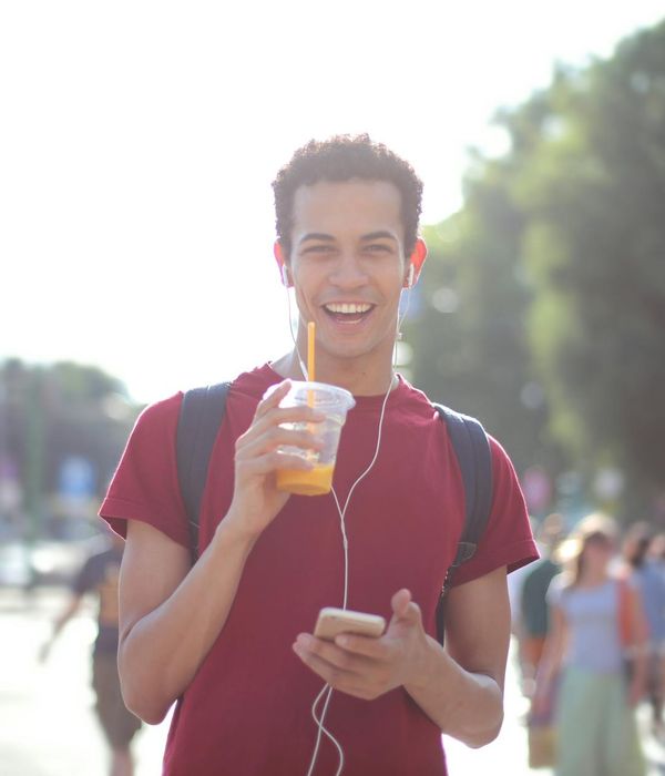 Smiling person stretching outdoors, looking refreshed and happy.